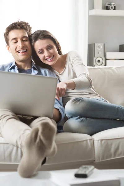 Par avkopplande soffan med laptop — Stockfoto