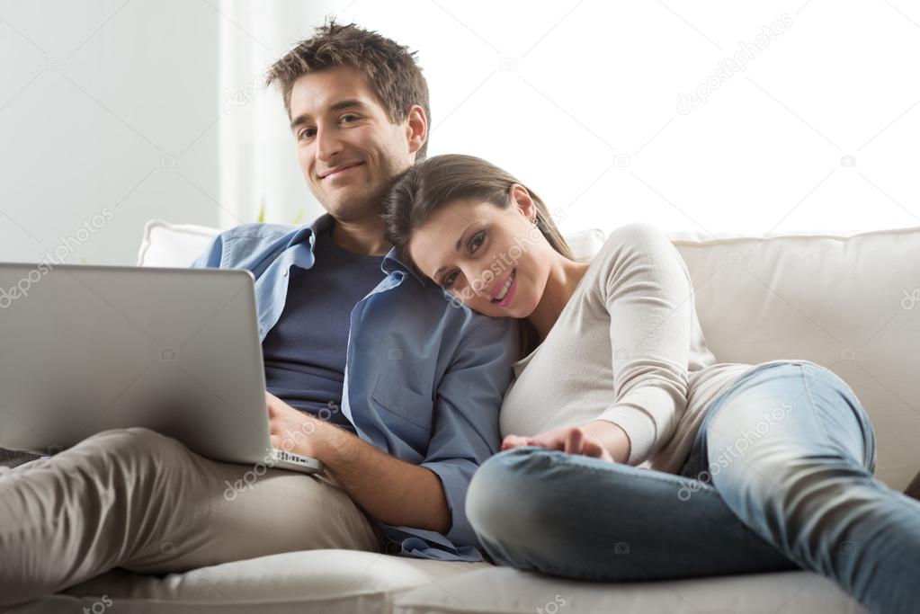 Couple relaxing on sofa with laptop