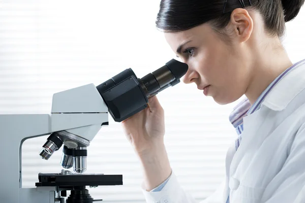 Kadın araştırmacı mikroskop kullanarak — Stok fotoğraf