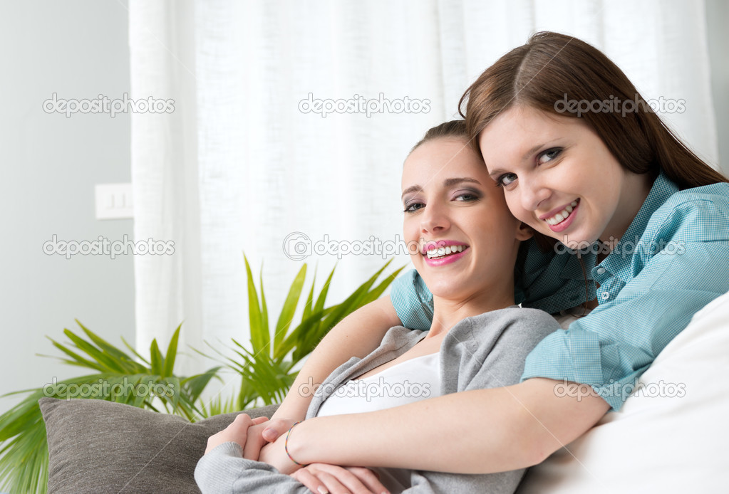 Girlfriends hugging on sofa