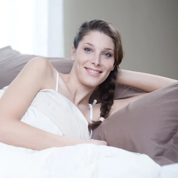 Mujer sonriendo mientras está acostada en la cama —  Fotos de Stock