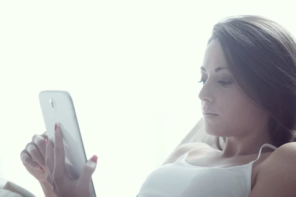 Junges Weibchen liegt mit Tablette auf ihrem Bett — Stockfoto