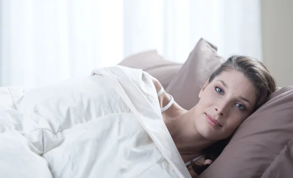En vacker ung kvinna liggande i sängen — Stockfoto