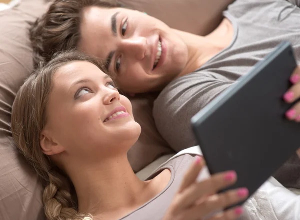 Amigos deitados na cama usando um tablet digital — Fotografia de Stock