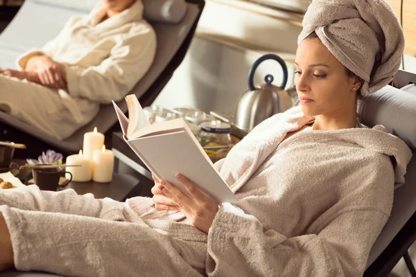 A gyönyörű nő pihentető wellness feküdt a kanapén, és az olvasás — Stock Fotó