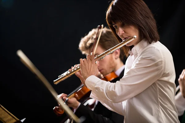 Vrouwelijke fluitist met orkest op het podium — Stockfoto