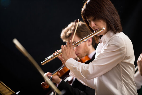Female flutist with orchestra on stage