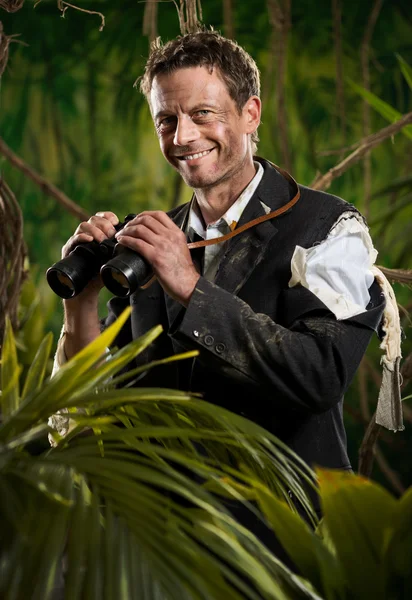 Jistý podnikatel drží dalekohled a poznáním jungle. — Stock fotografie