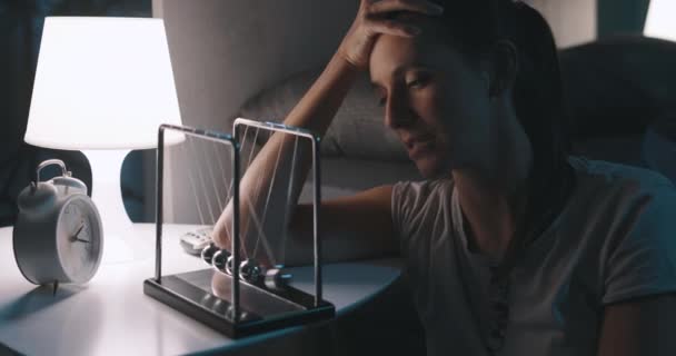 Triste kvinde, der lider af søvnløshed og stirrer på Newtons vugge – Stock-video