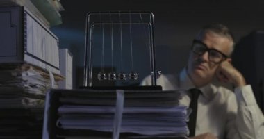 Üzgün ofis çalışanı Newton 'un beşiğine bakıyor.