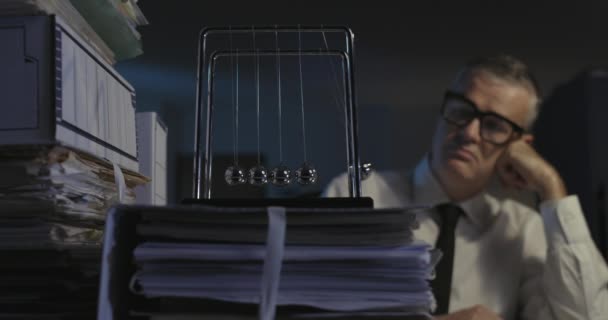Smutny pracownik biurowy gapiący się na kołyskę Newtona — Wideo stockowe