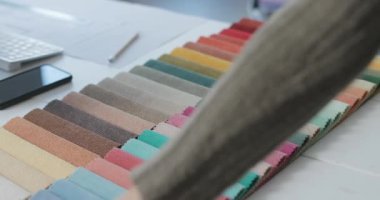 Masadaki renkli kumaş örneklerine dokunan kadın.