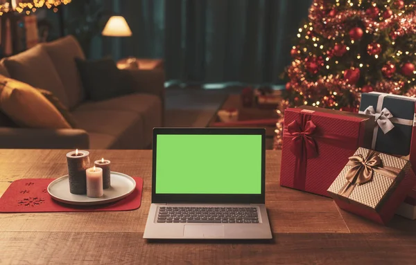 笔记本电脑 桌子上有空白屏幕 有礼物 背景上有圣诞树 — 图库照片