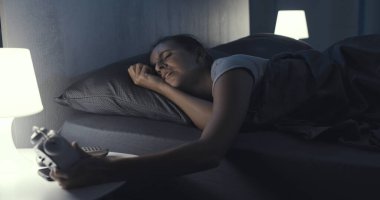 Üzgün kadın yatakta yatıp çalar saati kontrol ediyor. Uykusuzluk çekiyor.