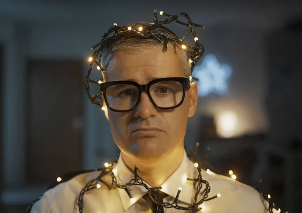 悲观失望的生意人在圣诞节工作 他被圣诞灯包裹着 — 图库照片