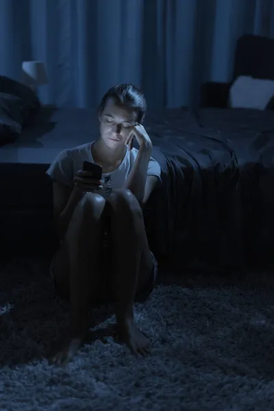 Уставшая Женщина Сидящая Рядом Своей Кроватью Проверяя Свой Смартфон Поздно — стоковое фото