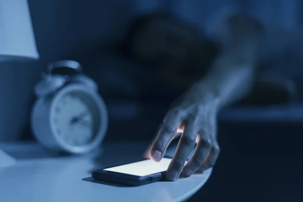 女人睡在床上 深夜接到一个电话 她正在检查她的智能手机 — 图库照片