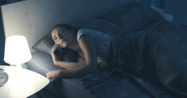 Gecenin bir yarısı akıllı telefonundan bir telefon alan bir kadın.