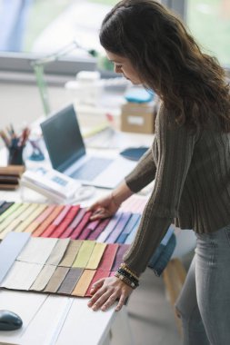 Stüdyosunda çalışan profesyonel bir dekoratör. Projesi için kumaş örnekleri seçiyor.