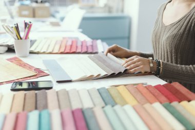 Proje için kumaş örnekleri seçen profesyonel bir dekoratör. Eller yukarı.
