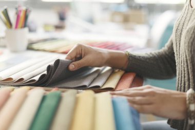 Proje için kumaş örnekleri seçen profesyonel bir dekoratör. Eller yukarı.