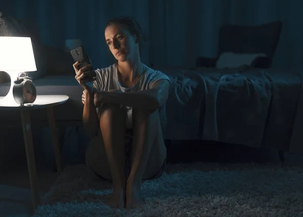 Wanita Yang Kelelahan Duduk Samping Tempat Tidurnya Dan Memeriksa Smartphone — Stok Foto