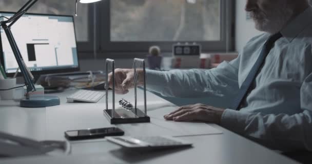 Businessman playing with Newton's cradle balance balls — Stock Video