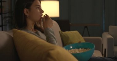 Patlamış mısır yiyen ve televizyon izleyen bir genç.