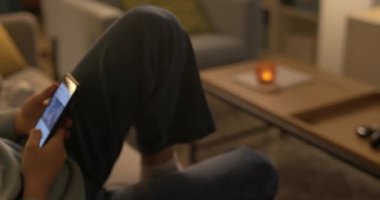 Ergen kız kanepede oturuyor ve telefonuyla sosyal iletişim kuruyor.