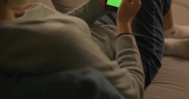 Kanepede oturan ve akıllı telefonunu kullanan bir kadın.