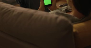 Kanepede oturan ve akıllı telefonunu kullanan bir kadın.