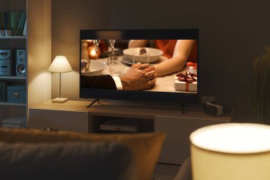 Televizyonda ve oturma odasında romantik komedi filmi yayınlanıyor.