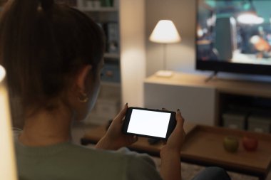 Ergen, evdeki kanepede dinleniyor ve akıllı telefonunu kullanarak internete bağlanıyor.
