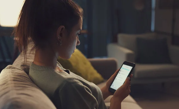 Young Woman Sitting Sofa Living Room Connecting Online Her Smartphone — Stock fotografie