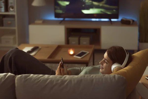 Teenager Relaxing Sofa Living Room She Wearing Headphones Connecting Online — Stock Fotó