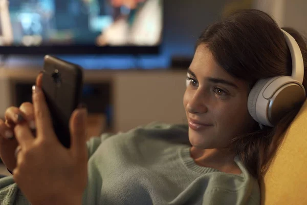 Smiling Teenager Lying Couch Connecting Her Smartphone She Wearing Headphones — Stock Photo, Image