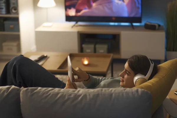 Young Woman Wearing Wireless Headphones Connecting Her Tablet She Lying — Foto de Stock