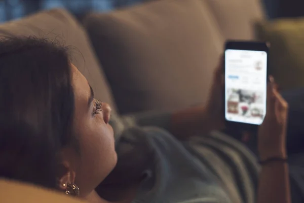 Kız Evde Dinleniyor Kanepede Uzanıyor Akıllı Telefonuyla Internete Bağlanıyor — Stok fotoğraf