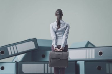 İş kadını çantasını tutuyor ve bir sürü dağınık yüzük klasörüne bakıyor.