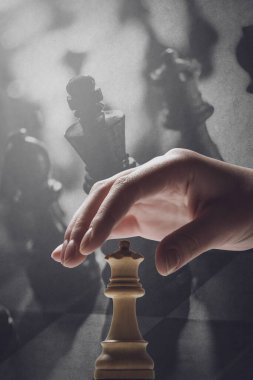 Profesyonel satranç oyuncusu arka planda bir taşı ve satranç oyununu oynatıyor