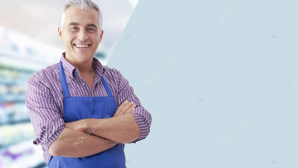 Confident grocery store clerk posing with arms crossed and smiling, blank copy space