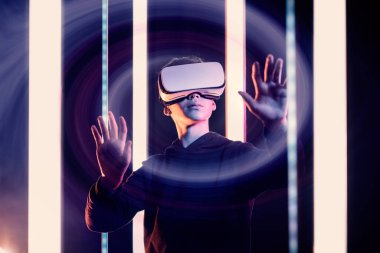 Genç kullanıcı bir VR kulaklık takıyor ve sanal gerçeklik, metaevren ve dijital dünya konseptini deneyimliyor