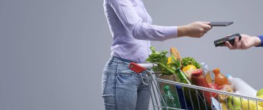 Akıllı telefonuyla alışveriş yapan bir kadın. NFC ödeme konsepti.