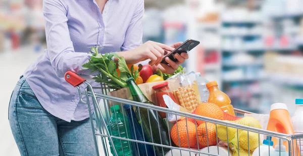 Frau Lehnt Einkaufswagen Und Bedient Ihr Smartphone Supermarkt — Stockfoto