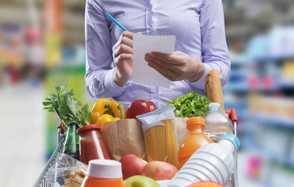 Mulher Verificando Uma Lista Compras Comprando Mercadorias Supermercado Seu Carrinho — Fotografia de Stock