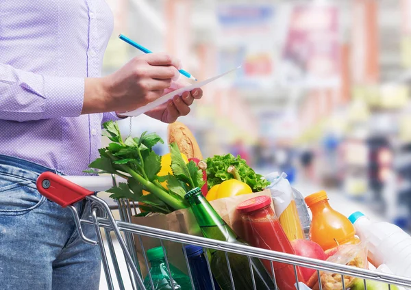 Mulher Verificando Uma Lista Compras Comprando Mercadorias Supermercado Seu Carrinho — Fotografia de Stock