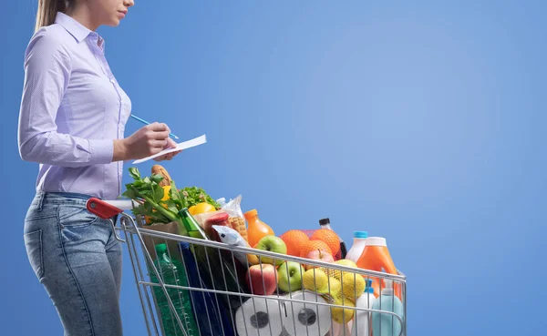 Frau Überprüft Einkaufsliste Und Einkaufswagen Voller Frischer Waren Lebensmitteleinkaufskonzept — Stockfoto