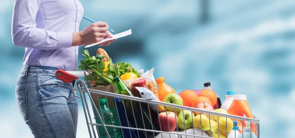 Mulher Escrevendo Uma Lista Compras Comprando Mercadorias Supermercado Seu Carrinho — Fotografia de Stock