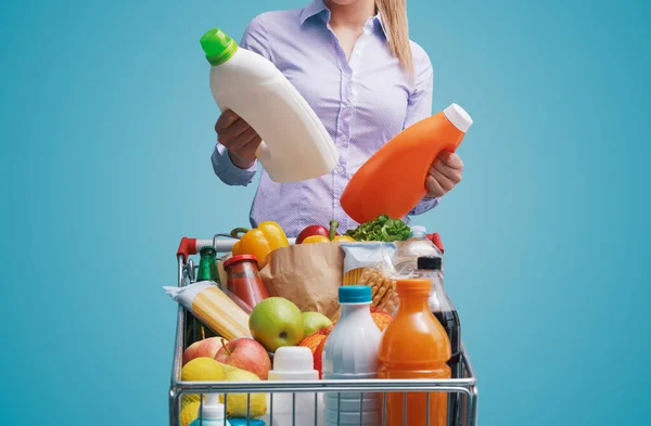 スーパーで食料品の買い物をして商品を比較している女性 彼女は洗濯洗剤の2本のボトルをチェックしています — ストック写真