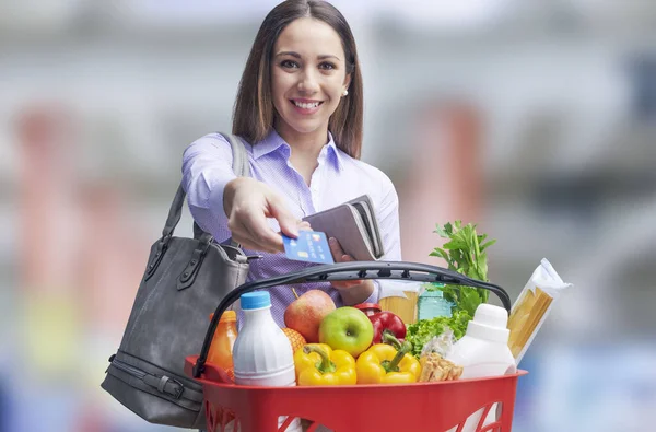 拿着满满的购物篮 用信用卡支付食品杂货的女人 — 图库照片